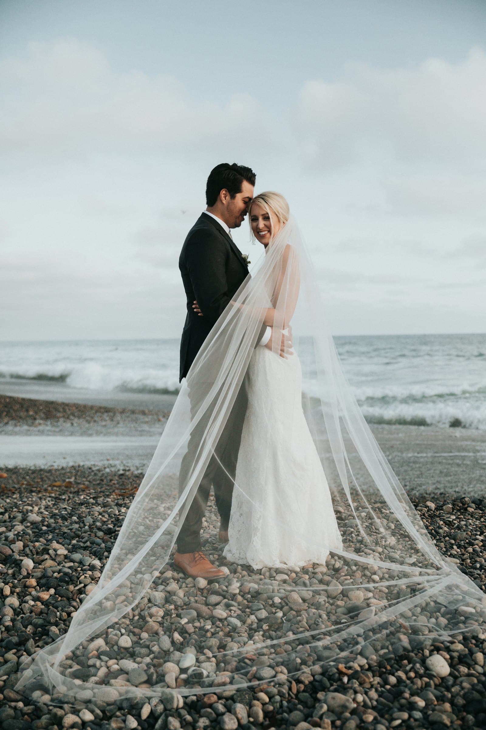 Novios en la playa con el velo al viento